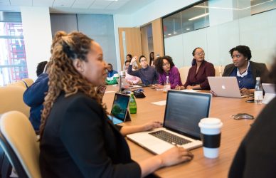 Group of People Sitting on Chair in Front of Wooden Table Inside White Painted Room