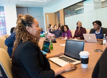 Group of People Sitting on Chair in Front of Wooden Table Inside White Painted Room